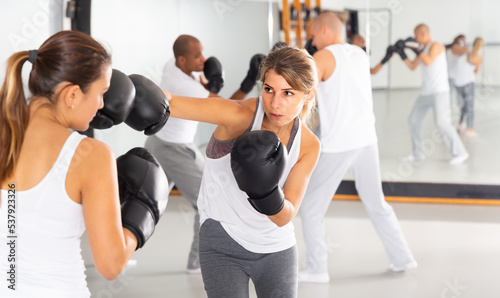 Active young woman mastering self defense techniques, practicing punches at boxing gym