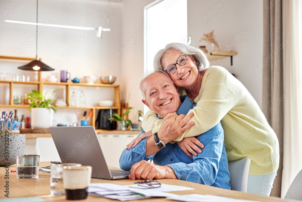 Elderly couple hugging while paying bills Elderly couple hugging while paying bills