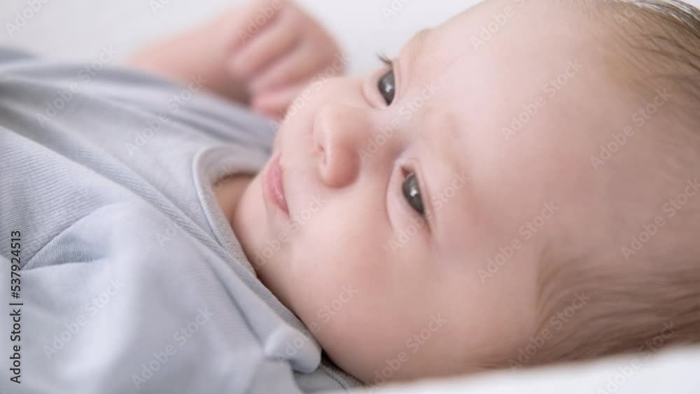 Portrait newborn baby boy lying in nursery cocoon with blue clothes on bed in bedroom at home, happy baby morning Portrait newborn baby boy lying in nursery cocoon with blue clothes on bed in bedroom at home, happy baby morning