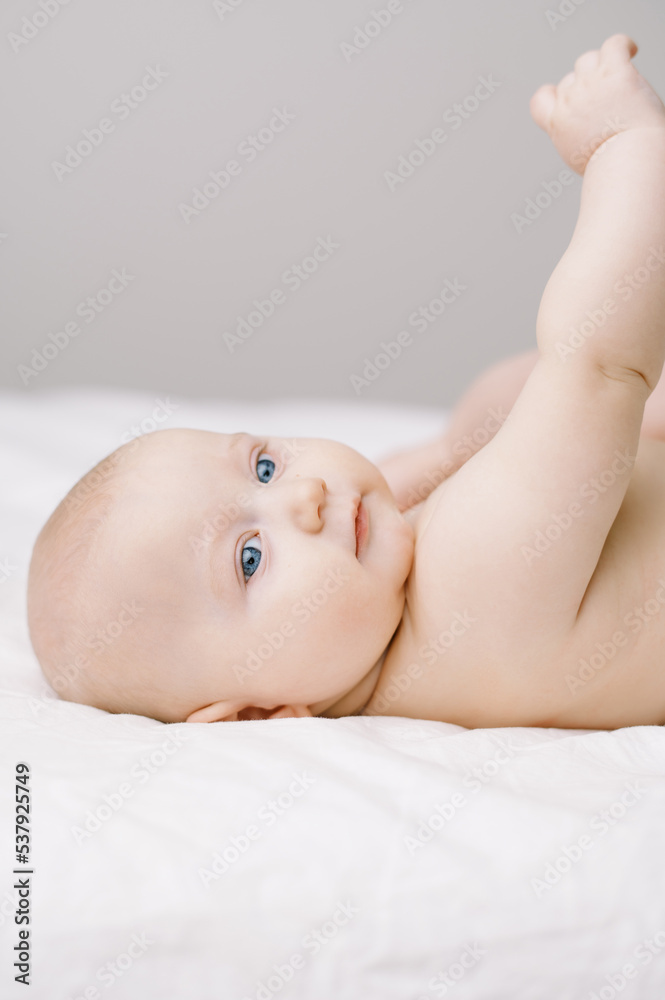 Portrait of a baby in a diaper on a bed with white sheets Portrait of a baby in a diaper on a bed with white sheets