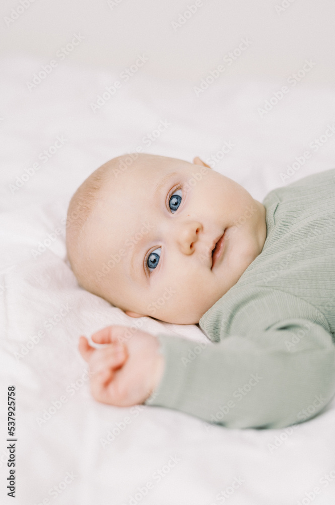 Portrait of a baby in a diaper on a bed with white sheets Portrait of a baby in a diaper on a bed with white sheets