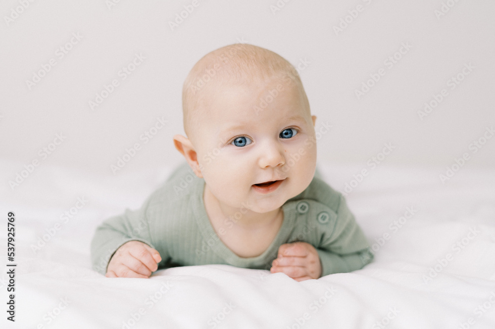 Portrait of a baby in a diaper on a bed with white sheets Portrait of a baby in a diaper on a bed with white sheets