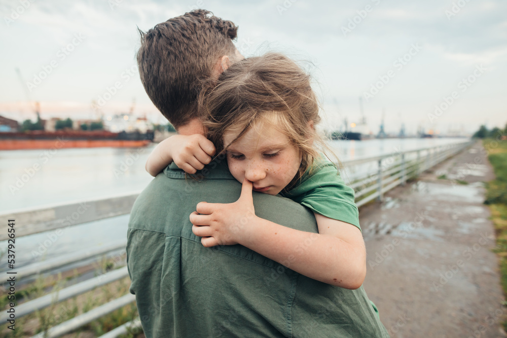 Upset little girl in father's arms Upset little girl in father's arms