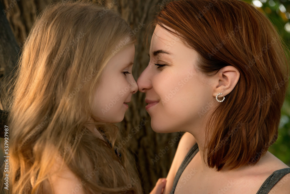 Mother and daughter embrace in the park. Close-up portrait of woman and little girl spend time together outdoor. Mom and her child. Family concept Mother and daughter embrace in the park. Close-up portrait of woman and little girl spend time together outdoor. Mom and her child. Family concept