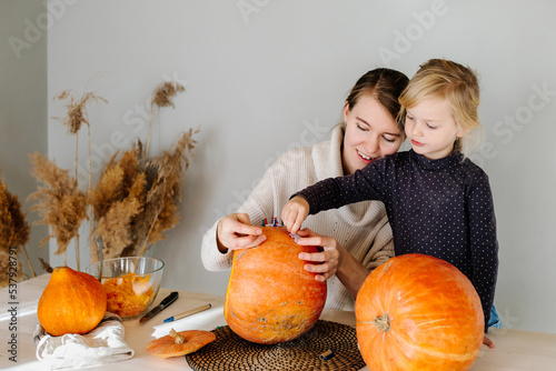 Mother and daughter attaching stencil to pumpkin photo