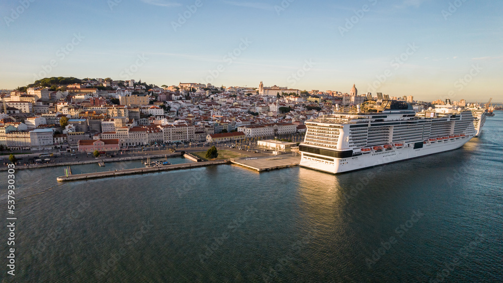 aerial drone view of a large cruise ships moored at Lisbon port, Portugal with Lisbon landmarks in the background