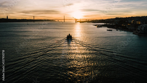 Wake of nautical vessel at sunset on Tagus River in Lisbon, Portugal with 25 April Bridge in the background photo