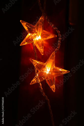 Christmas wallpaper.Star burning on a brown wooden background in warm colors.Festive glowing garlands on a dark background.