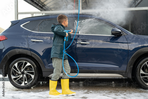 Kid is washing vehicle at manual car wash station