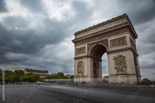 Arc de Triomphe at dramatic sky with storm clouds and blurred car, Paris, France