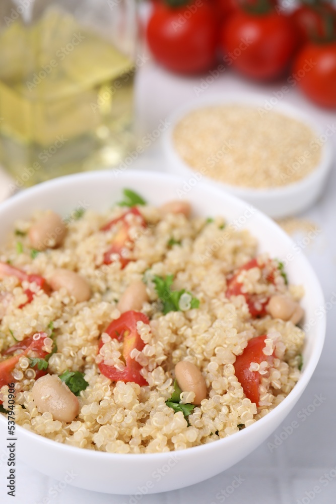Delicious quinoa salad with tomatoes, beans and parsley served on white tiled table, closeup Delicious quinoa salad with tomatoes, beans and parsley served on white tiled table, closeup