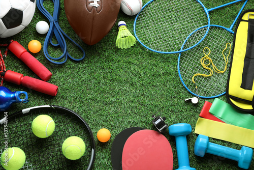 Set of different colorful sports equipment on green grass, flat lay. Space for text