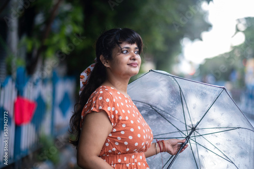 Indian woman withstanding beside roan in a rainy day at outdoors 