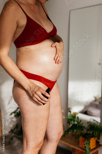 a pregnant young woman’s applying an essential oil treatment photo