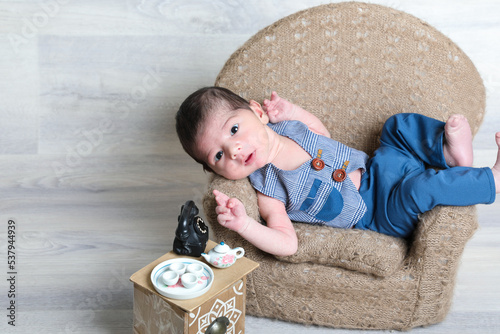 new born baby boy in beautiful dress lying at little chair,tiny stool small toys,face expressions