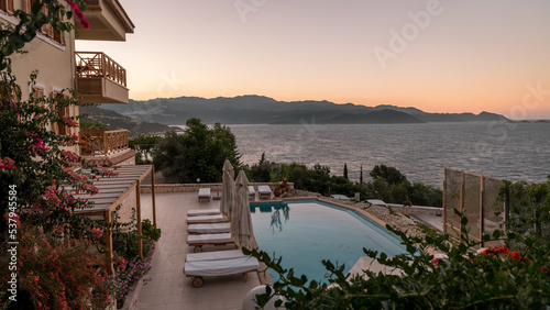Fototapeta Naklejka Na Ścianę i Meble -  beach chairs with white umbrellas looking out over the ocean in Turkey on a summer day, beach beds on rocks looking out over the ocean