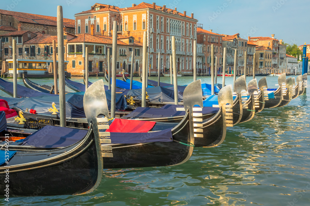 Gondolas in Grand Canal stake pier at golden sunset, Venice, Italy