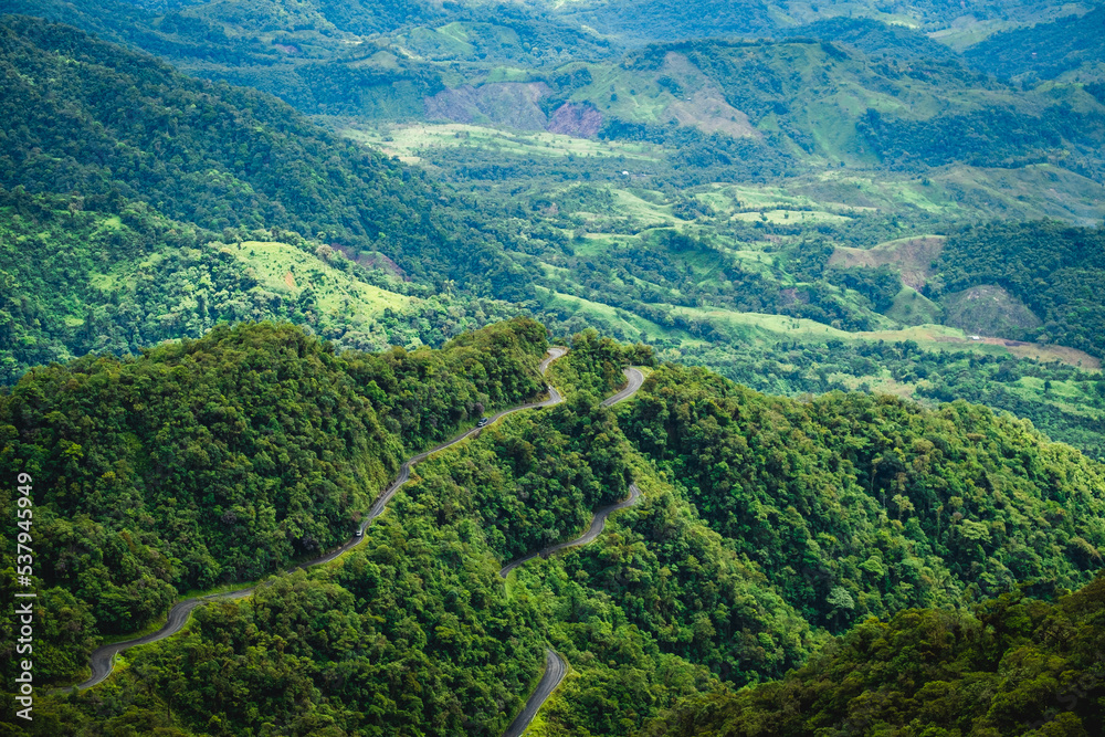 switchback road narrowed dirt path over the andes mountains red forest jungle green vegetation 
