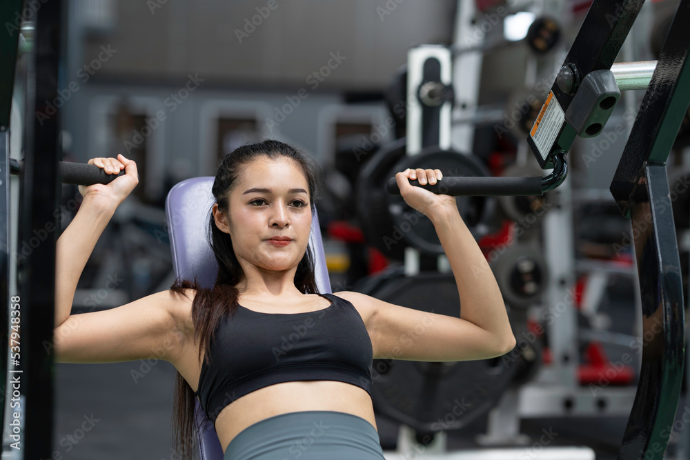Beautiful fit woman trains in the gym, fitness. woman flexing muscles on chest press gym machine, Concept Sport, passion. Beautiful fit woman trains in the gym, fitness. woman flexing muscles on chest press gym machine, Concept Sport, passion.