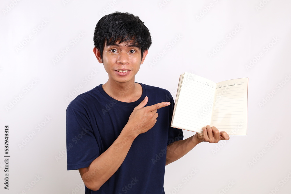Happy young asian man standing while presenting his book. Isolated on white background Happy young asian man standing while presenting his book. Isolated on white background