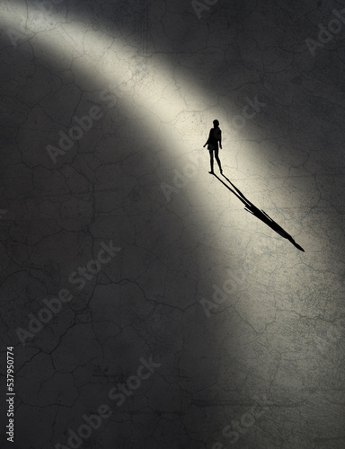 A young girl’s body language says she is feeling vulnerable and insecure as she finds herself along in a shaft of light in this 3-d illustration. photo