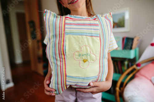 Girl holds handmade pillow she sewed
