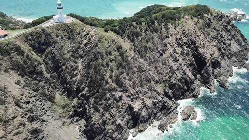 Drone aerial over beautiful blue water panning up to show lighthouse on a sunny day photo