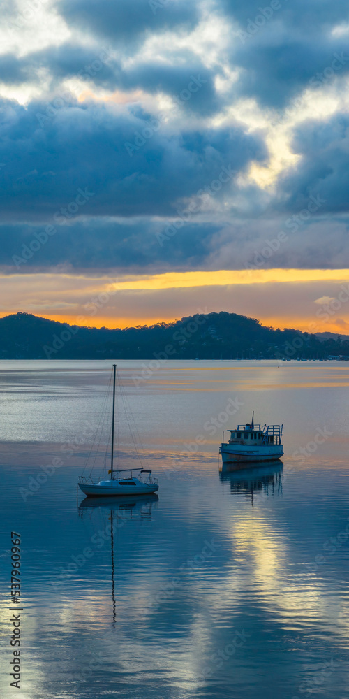 Aerial sunrise waterscape with boats, rain clouds and reflections