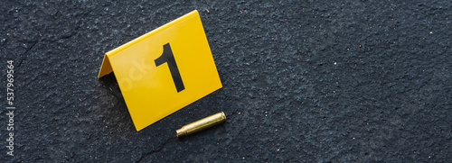 One yellow crime scene evidence marker on the street after a gun shooting brass bullet shell casing rifle