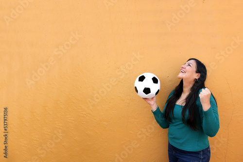 Latino adult woman plays with a soccer ball very excited that she is going to see the World Cup and wants to see her team win