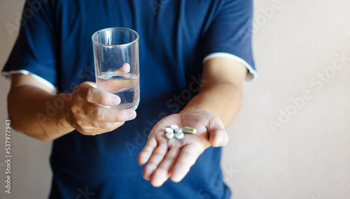 Closeup man holds glass of water and pills to take medicine. Concept : Health care, health problem, sickness and remedy. Basic self take care at home when get sick. 