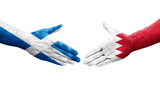 Handshake between Bahrain and Scotland flags painted on hands, isolated transparent image.