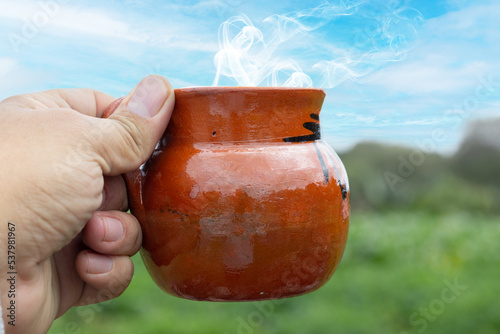 personal perspective of man holding tradonal cup of mexican coffee in field photo