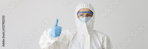 Doctor in protective suit holds thumbs up gesture