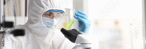 Scientist in protective suit studies toxic poisonous liquids in laboratory