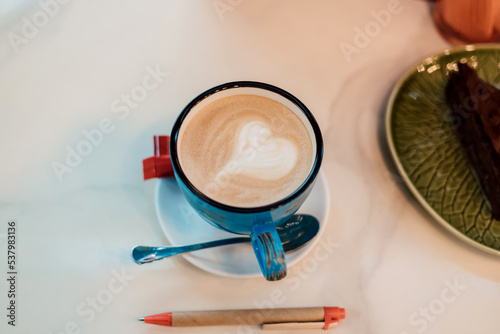 View from above. Coffee with milk in a blue cup on a wooden table in a cafe