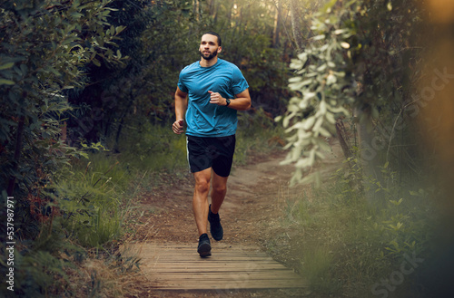 Fototapeta Naklejka Na Ścianę i Meble -  Fitness, man and running in nature for healthy exercise, training and workout in the outdoors. Active, athletic male runner in sports taking a jog in the forest or park for health and cardio wellness