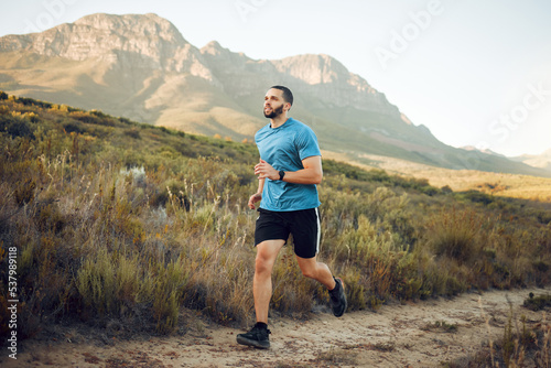 Running, fitness and mountain nature park road run of a man runner outdoor for exercise. Training, sport and workout of a athlete with fast energy and stamina on a walking and hiking dirt trail