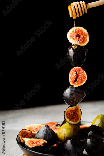 ripe figs on a plate, dark background and drops of honey