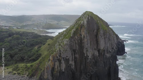Drone circle around rocky cliff with green grass and rolling hills in Transkei, South Africa photo