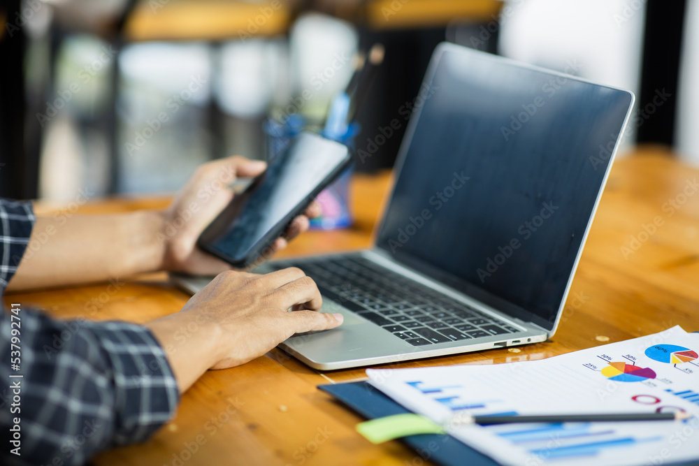 young man working at home using smartphone at work Documents on office desk with laptop computer and business plan graph with social diagram. young man working at home using smartphone at work Documents on office desk with laptop computer and business plan graph with social diagram.