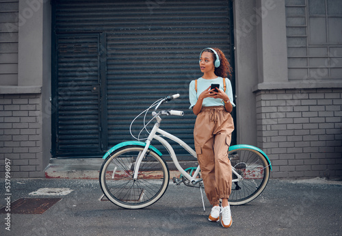 Phone, bike and city travel for woman with music headphones, podcast or radio in London city. Thinking fashion student, mobile or cool model with eco friendly and future environment energy transport