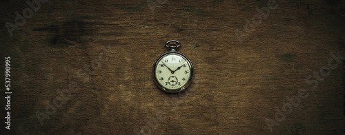 Round mechanical clock on a wooden background in vintage style. Retro watch with a stopwatch on a rectangular brown table.