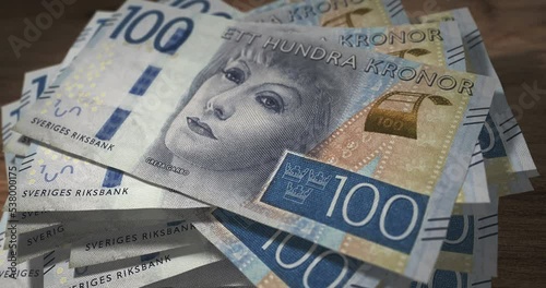 Swedish Krona 100 SEK banknotes falling on the table. Sweden currency paper notes count on stack. Timelapse of money counting. 3D concept. photo