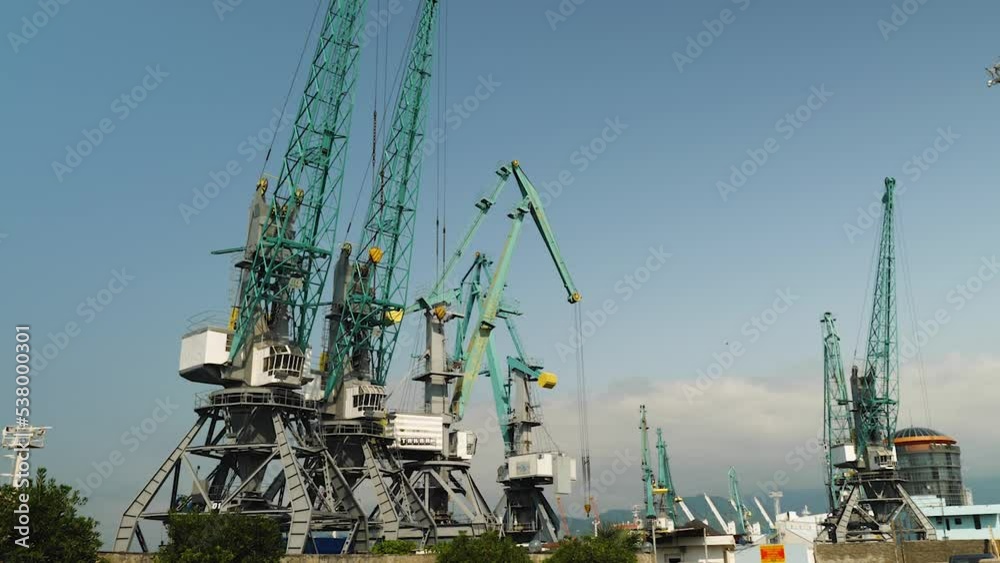 Port cranes at work. A harbor sea crane unloads a ship in port. Concept of industry and transport Port cranes at work. A harbor sea crane unloads a ship in port. Concept of industry and transport
