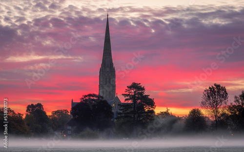 October misty morning sunrise behind Salisbury Cathedral from the Harnham water meadows Wilitshire south west England photo