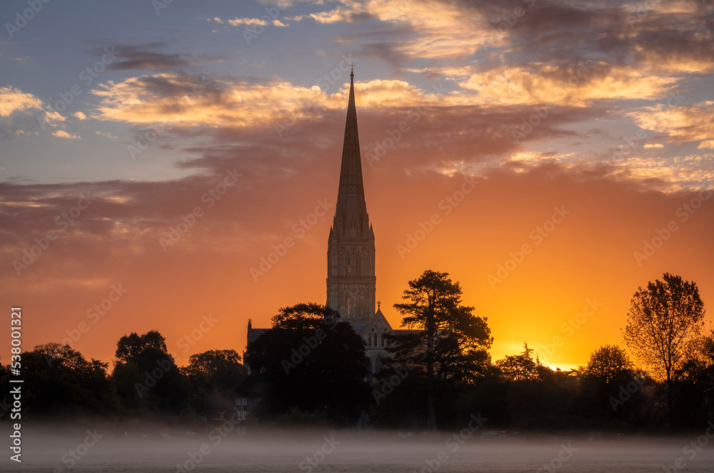 October misty morning sunrise behind Salisbury Cathedral from the Harnham water meadows Wilitshire south west England