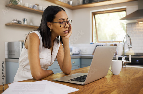 Stress, burnout and laptop with woman in kitchen with mental health, tired or depression from remote work. Review, sad and research with bored girl reading email at home for news, idea and technology