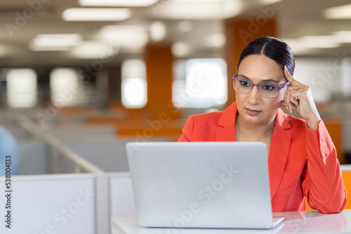 pretty indian businesswoman using laptop in office
