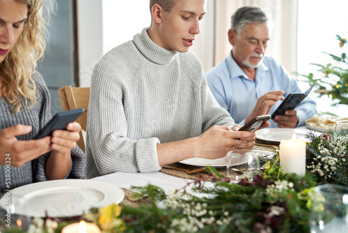 Family of caucasian people sitting in silence and using phones during Christmas Eve
